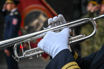 Muzičar svira trubu. Vojnik u bijelim rukavicama svira trubu. Vojni orkestar na paradi.