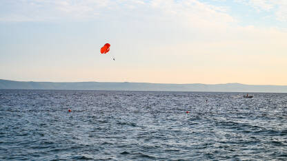 Padobran i čamac na moru tokom ljeta. Turist se zabavlja s padobranom na nebu. Ekstremni sport i avantura. Parasailing.