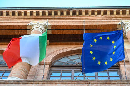 Italijanska i zastava EU se vijori na vjetru. Zastava Italije i Europske unije vijori se na zgradi. Simbol Italije i EU.