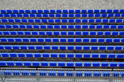 Plastične plave stolice na tribinama stadiona. Redovi stolica za publiku.