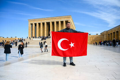 Muškarac drži zastavu Republike Turske. Ljudi ispred mauzoleja Anitkabir. Anıtkabir je počivalište Mustafe Kemala Ataturka.