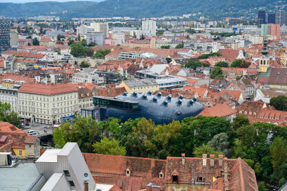 Graz, Austrija: Panoramski pogled na grad. Zgrade, kuće, ulice i crveni krovovi Graza. Zgrada Kunsthausa ili muzeja umjetnosti. Stari grad, pogled s dvorca.