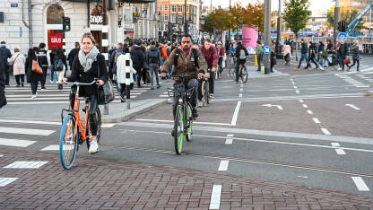 Amsterdam, Nizozemska: Grupa biciklista vozi bicikle po ulici. Biciklizam u  gradu. Ljudi koriste bicikle za vožnju.