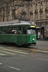 Deo zelenog tramvaja fotografisan u pokretu, Velika zgrada u pozadini