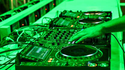 DJ pušta muziku sa opremom na festivalu. Profesionalni CD plejer i mikser zvuka. DJ u noćnom klubu.