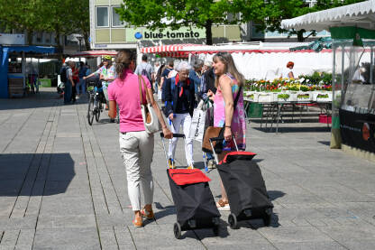 Žene sa torbama na ulici. Žene kupuju voće i povrće na lokalnoj pijaci.