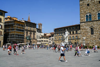 Firenze, Italija: Turisti istražuju grad. Neptunova fontana na Piazza della Signoria. Ljudi šetaju trgom. Zgrade u centru grada.