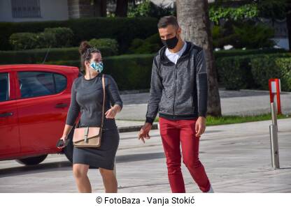 Muškarac i žena hodaju ulicom sa maskama na licu zbog pandemije virusa korona.