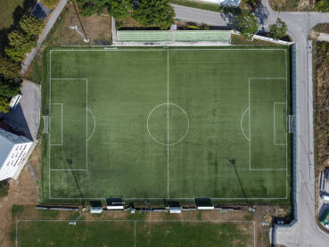 Fudbalski stadion, snimak dronom. Zeleni sportski teren. Vještačka trava na stadionu. Sportski teren. Bijele linije na terenu stadiona.