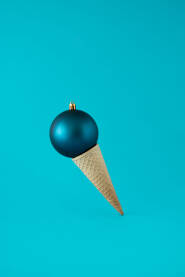 Sladoled od plave božićne, novogodišnje kuglice i korneta na plavoj pozadini.