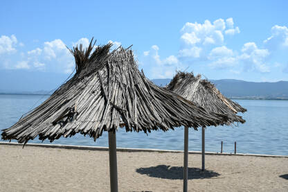 Suncobrani na plaži. Dojransko jezero, Sjeverna Makedonija. Pješčana plaža pored jezera.