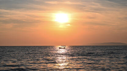 Ribolovni čamac na moru tokom zalaska sunca. Ribolov na moru.