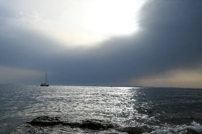 Nevrijeme na moru. Čamac na vodi. Valovi na moru s dramatičnim oblacima iznad. Kišni ljetni dan.
