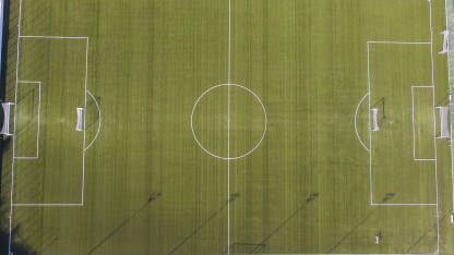 Fudbalsko igralište. Zelena trava na stadionu, pogled odozgo. Fudbalski stadion sa bijelim linijama i golovima, snimak dronom.