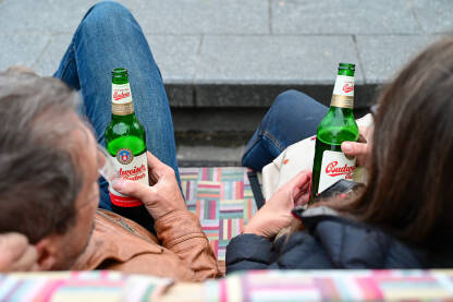 Turisti piju pivo na klupi. Par odmara na klupi i pije Budweiser pivo.