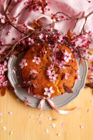 Torta ukrašena proljetnim rozim cvijetovima trešnje na stolu.