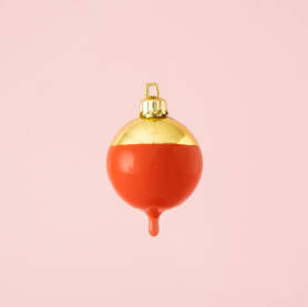 Zlatna ukrasna kuglica umočena u crvenu boju.