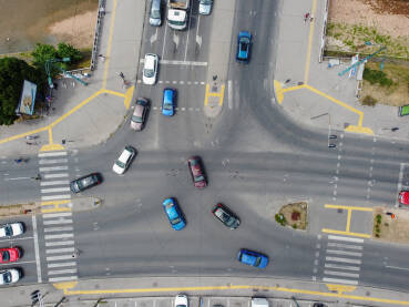 Raskrsnica sa autima u gradu, snimak dronom. utomobili i autobusi voze asfaltnom ulicom u gradu. Promet na cestama. Pješaci prelaze ulicu.