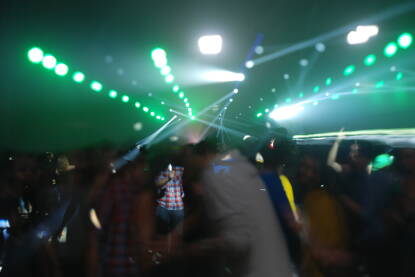 Grupa mladih osoba koje plešu na zabavi. Zamućena fotografija ljudi koji se zabavljaju pod svjetlima na koncertu. Ples na festivalu. House techno party. Noćni život.