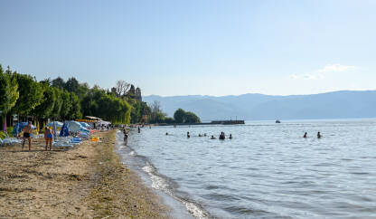 Ohridsko jezero, Sjeverna Makedonija. Turisti. Ohridsko jezero, Sjeverna Makedonija. Turisti na obali jezera. Ljudi se kupaju i sunčaju.