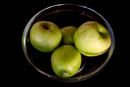 Četiri zelene jabuke u staklenoj zdjeli