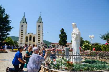 Katolički hodočasnici mole se u Međugorju, Bosna i Hercegovina. Ljudi prisustvuju svetoj misi. Crkva i kip Djevice Marije.