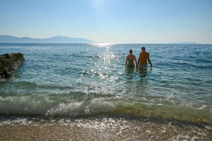 Par na ljetovanju na moru. Momak i djevojka u vodi. Ljudi plivaju. Turisti na odmoru.