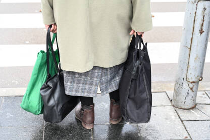 Starica nosi torbe s namirnicama na ulici. Starija žena sa torbama za kupovinu prelazi ulicu. Usamljena penzionerka nosi torbe u rukama.