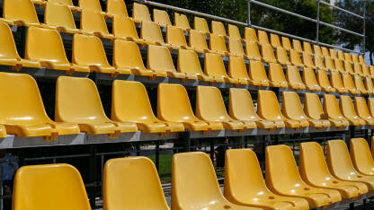 Mnogo plastičnih klupa za gledaoce na tribini. Mnogo plastičnih klupa za gledaoce na tribini. Plastične žute stolice. Plastične stolice na stadionu u redovima.