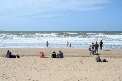 Ljudi na plaži na obali Sjevernog mora u Hagu, Nizozemska. Ljudi na plaži na obali Sjevernog mora u Hagu, Nizozemska. Pješčana plaža u Scheveningenu. The Hague ili Den Haag. Valovi na moru.