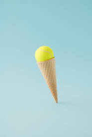 Kornet za sladoled s lopticom za tenis na plavoj pozadini.