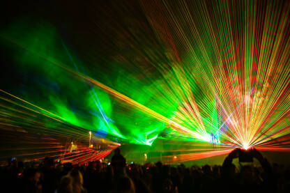 Laserska svjetla i dim na bini tokom koncerta. Raznobojna svjetlosna emisija noću. Apstraktna pozadina. Laserski snop.