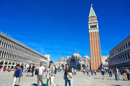Venecija, Italija: Ljudi šetaju glavnim trgom. Venecija, Italija: Ljudi šetaju glavnim trgom. Piazzetta San Marco. Popularna turistička destinacija. Zvonik, Bazilika svetog Marka i Duždeva palača u centru grada.