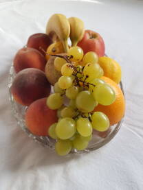 Staklena zdjela sa voćem (banane, breskve, kruška, limun, narandža, jabuka, bijelo grožđe)