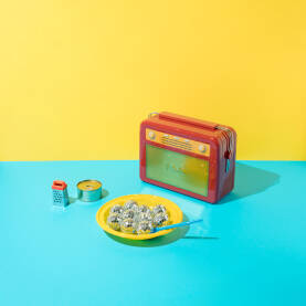 Retro radio, žuti plastični tanjur s disko kuglama i plavom plastičnom kašikom, te rende i konzerva.
