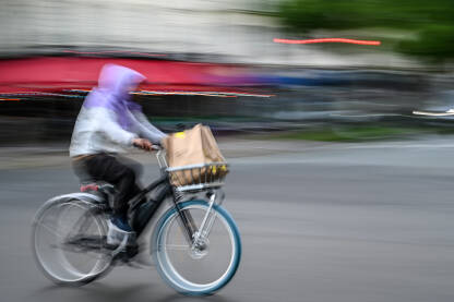 Čovjek se brzo kreće brzo na biciklu na ulici. Vožnja biciklom po gradu.