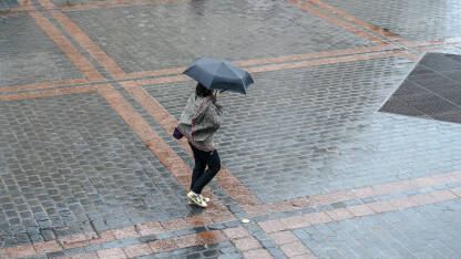 Djevojka sa kišobranom hoda po ulici po kiši.