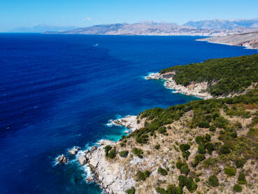 Divlja stjenovita plaža u Albaniji u blizini Ksamila i Sarande. Prekrasna prirodna kamena plaža i more ljeti. Valovi se lome na divljoj plaži, snimak iz zraka dronom.