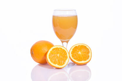 Cijele i narezane narandže sa čašom iscijeđenog soka na bijeloj pozadini