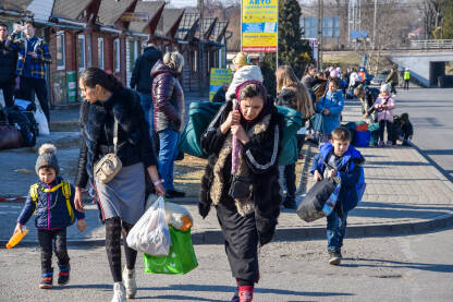 Žene i djeca na granici Ukrajina-Poljska. Ljudi iz Ukrajine bježe od rata. Žene i djeca nose kofere.