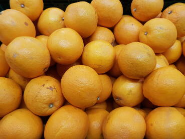 Narandže u gajbi na polici u marketu; prodaja narandži;