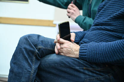 Čovjek drži mobilni telefon u rukama.