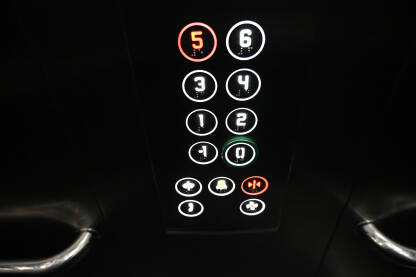 Tipke u liftu u zgradi. Osvjetljena upravljačka tabla u liftu. Brojevi na tipkama.
