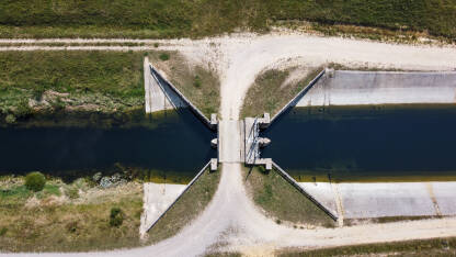 Brana na rijeci, snimak dronom. Betonska brana i riječni kanal u polju.