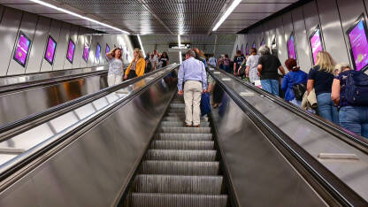 Ljudi na pokretnim stepenicama na stanici metroa. Putnici na pokretnim stepenicama u metrou.