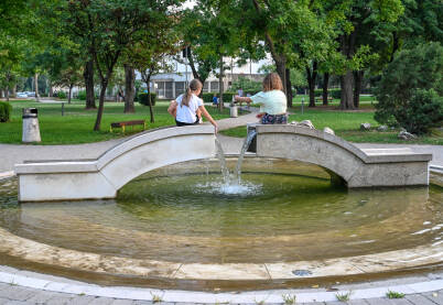 Djevojčice se igraju sa vodom u fontani u parku. Fontana u parku u Mostaru.