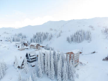 Vikendice i turistički objekti na planini zimi. Snimak dronom planine pod snijegom. Jahorina, BiH.