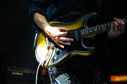 Muzičar svira električnu gitaru na koncertu, krupni plan. Muzički instrument.