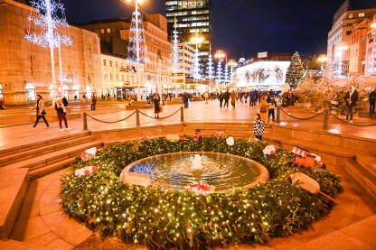 Advent u Zagrebu, Hrvatska. Ukrasi s lampicama na glavnom gradskom trgu. Ljudi se zabavljaju na Adventu na trgu baja Jelačića noću. Fontana Manduševac.