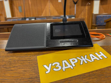 Sjednica u skupštini. Natpis SUZDRŽAN pored poslaničkog mikrofona.